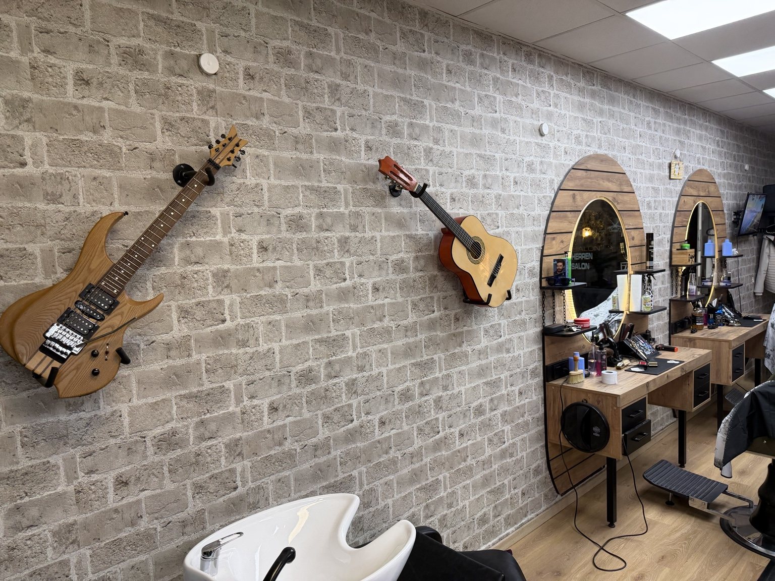 Zwei Gitarren an der Klinkerwand über dem Haarwaschbecken